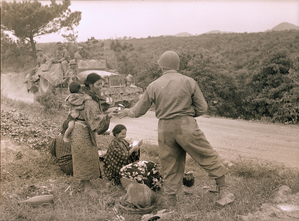 美軍士兵提供食物給路邊的日本婦女。迪奇‧施佩爾攝於1945年的沖繩。